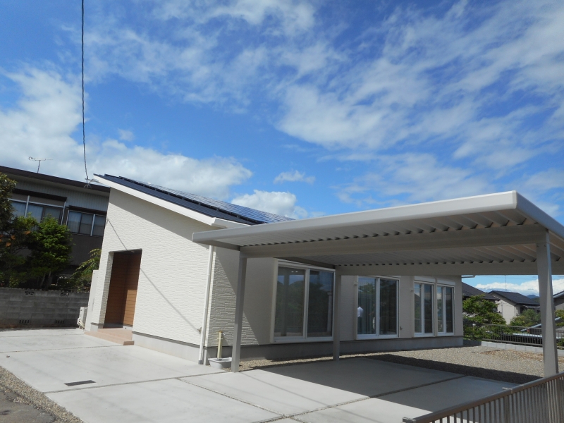 平屋造りながらの大きな屋根とガレージの上に太陽光パネルがびっしり載っています。