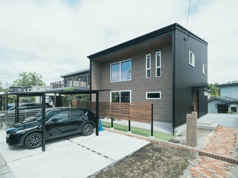 金属サイディングの無機質感と窯業系サイディングの木目のコントラストが目を引く外観。