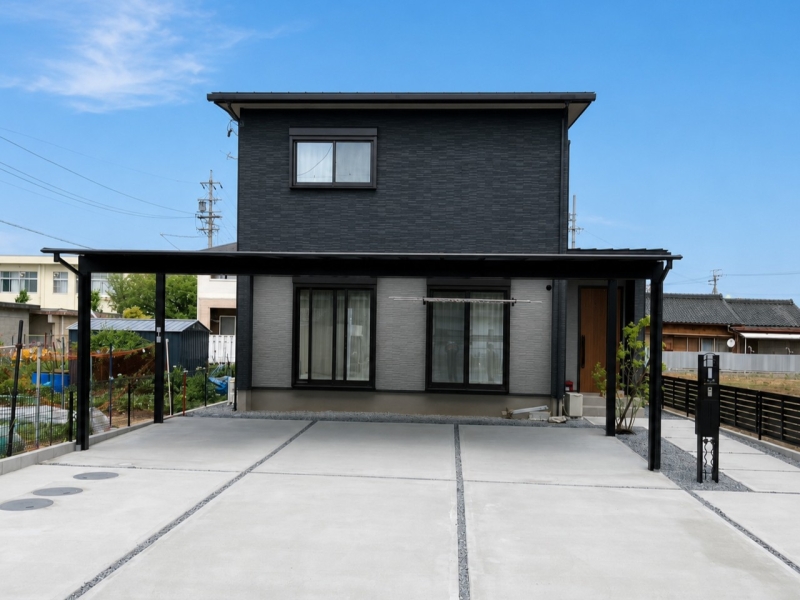 落ち着いたブラックの外観に、木目の玄関ドアがやさしいアクセントを添える住まい。 シンプルなデザインと機能的なカーポートが、毎日の暮らしを快適に支えます。
